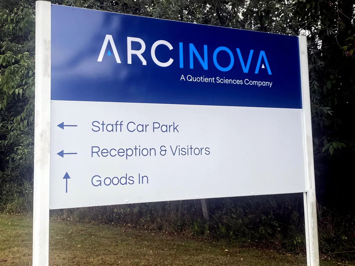 White printed ACM post sign for Arcinova with directional arrows, mounted on two posts
