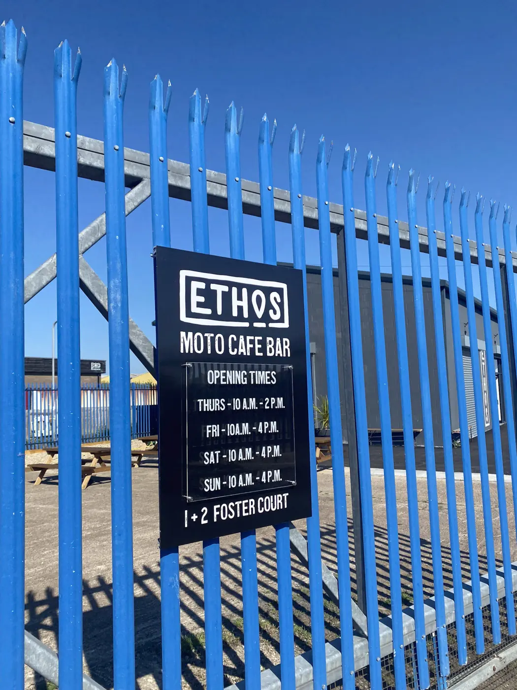 Opening hours panel fixed to blue railings for Ethos Moto Cafe Bar