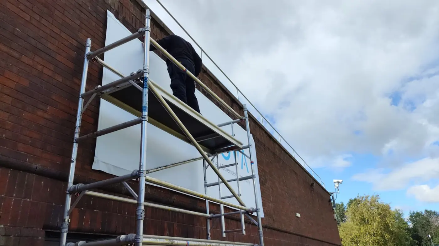 Fitting large panels to a brick building from a scaffold