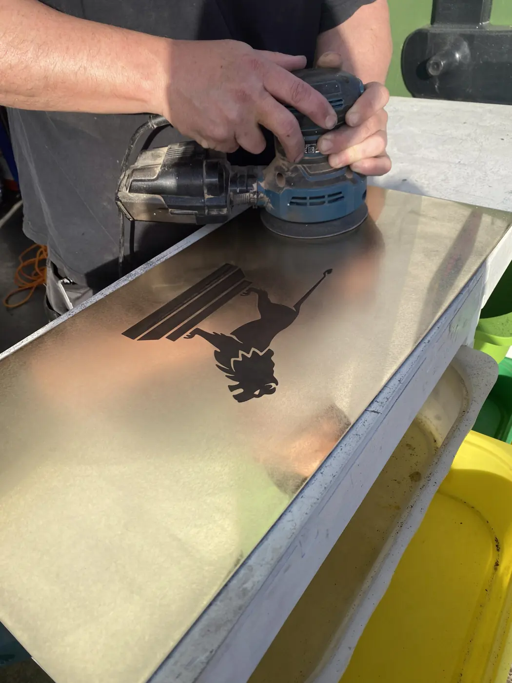 Sanding back a machined metal panel in the workshop